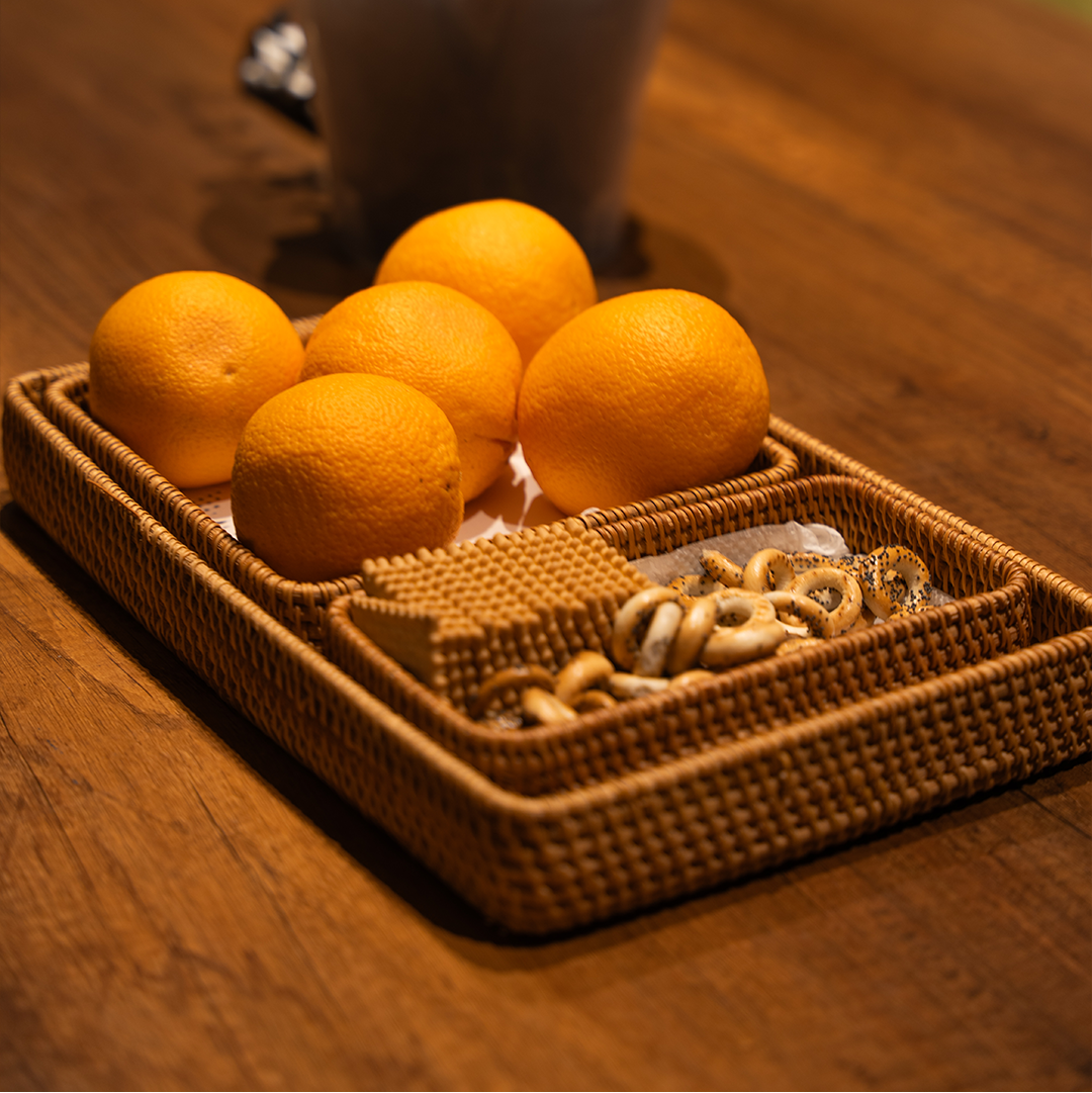 Handwoven rattan tray set styled with lemons and nuts
Rattan trays stacked on dining table
Detail shot of wicker weave texture
