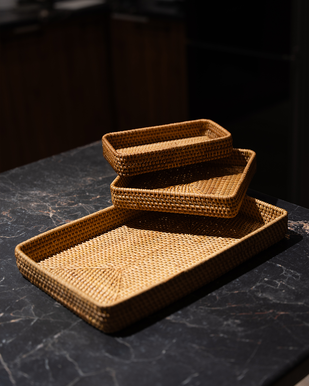 Handwoven rattan tray set styled with lemons and nuts
Rattan trays stacked on dining table
Detail shot of wicker weave texture
